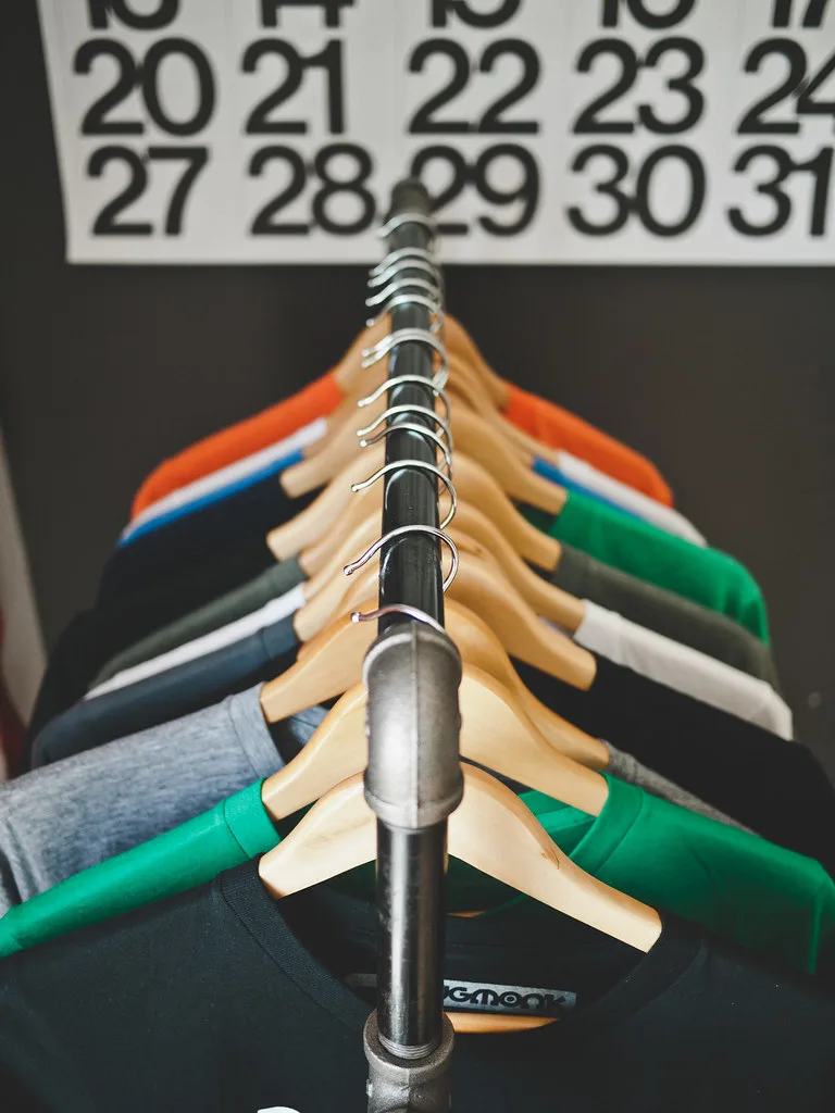 Folded brand tees hung on wooden hangers