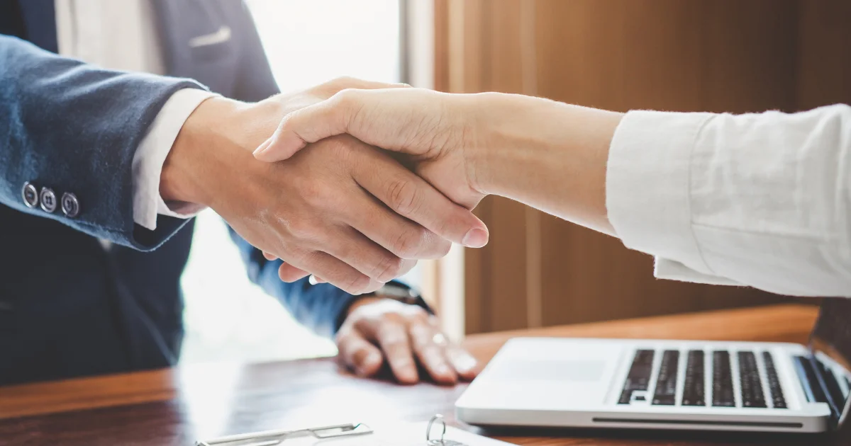 Founder and launch partner shaking hands over a laptop